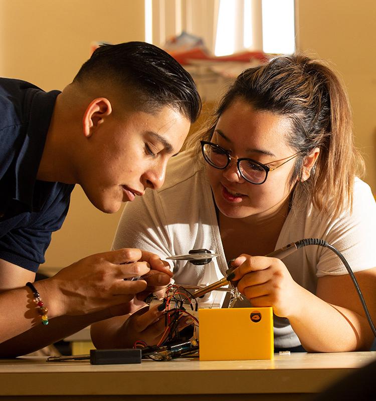 2名电子工程专业的学生在电路板上工作